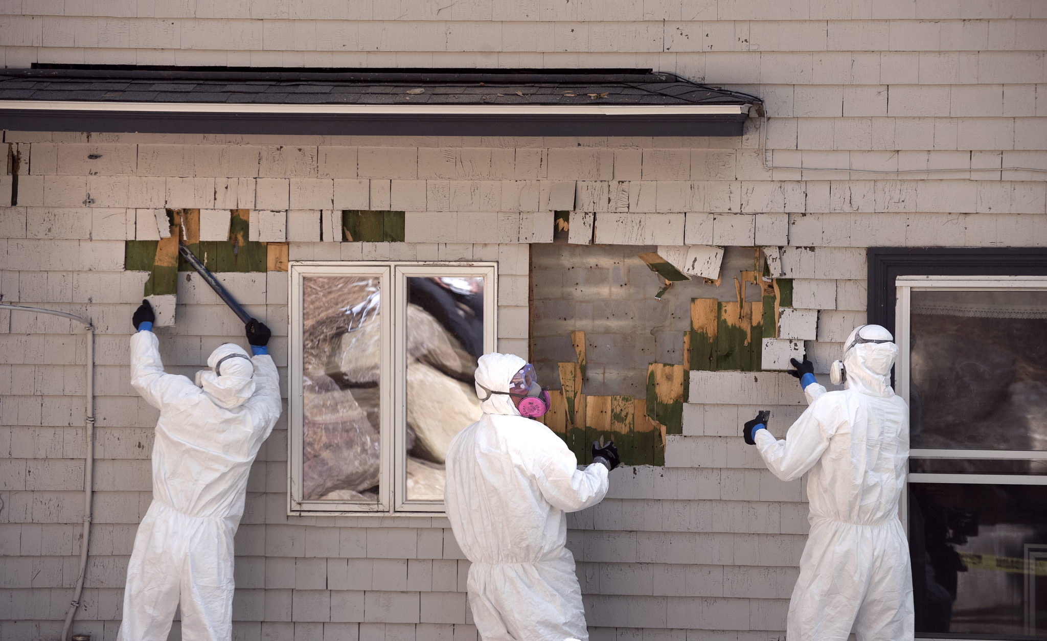 Workers remove cedar shingles, coated with lead-based paint from Jon and Briar Fishman’s camp in Northport, Maine, where lead hazards sickened their child. | Gabor Degre