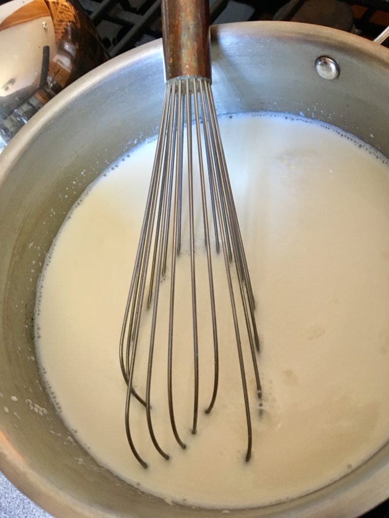 Whisk the cup of milk/yogurt mixture into the larger pot of heated milk.