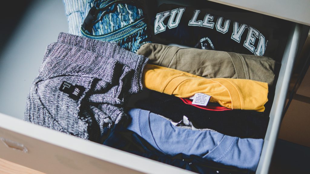 Shirts and sweaters neatly organized in a drawer.