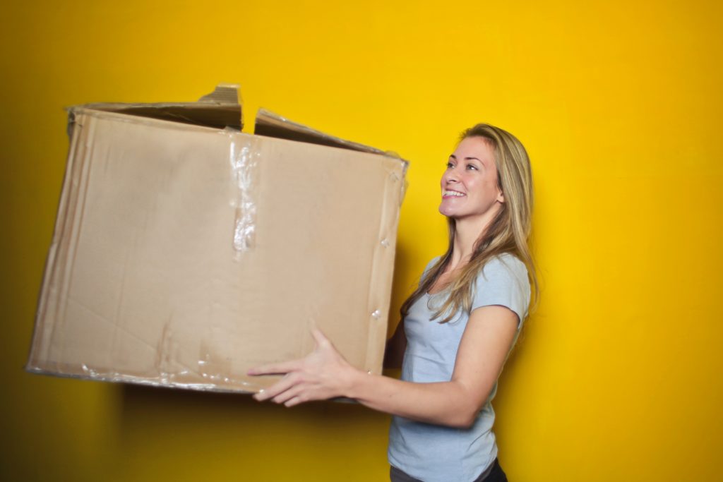 A woman holding a cardboard box of clothing to donate
