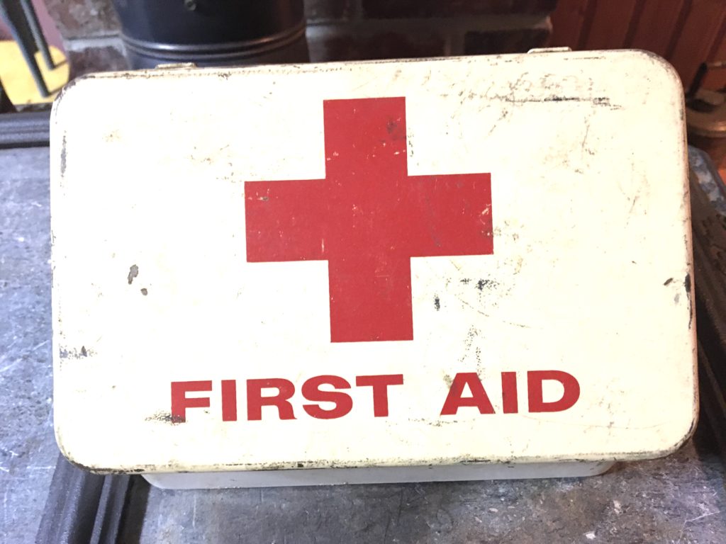 A metal first aid box with a giant red cross on it.