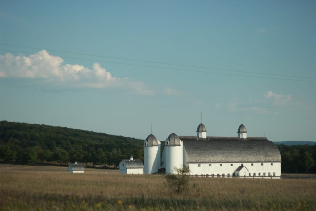 A large white barn with two grain silos.