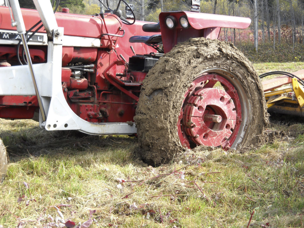 A large farm tractor stuck in the mud.